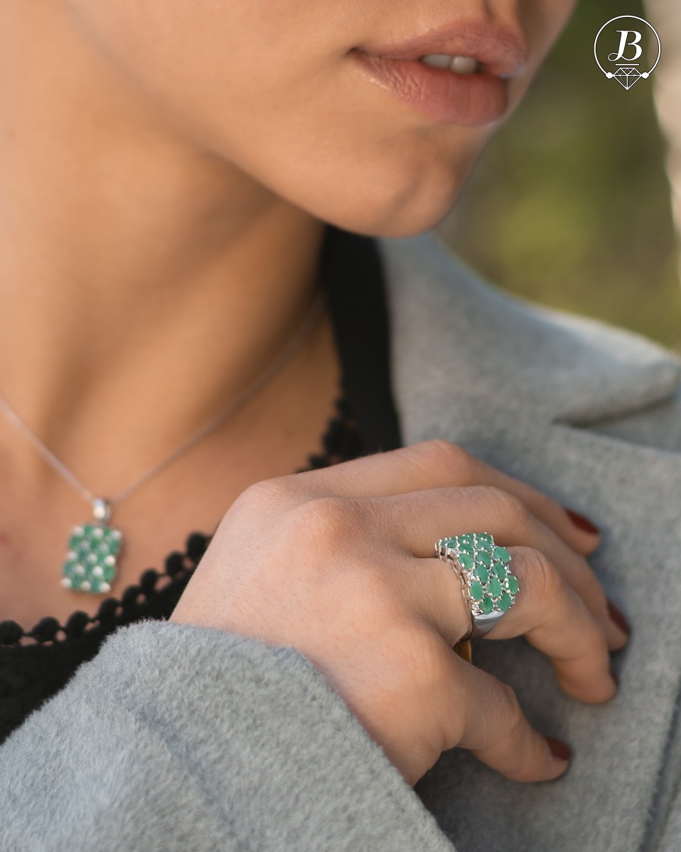 Women's ring with modern craftsmanship, combining numerous fine natural emerald stones, complemented by the sparkle of zircons and made entirely of rhodium-plated silver. In a charming set with matching necklace and earrings.