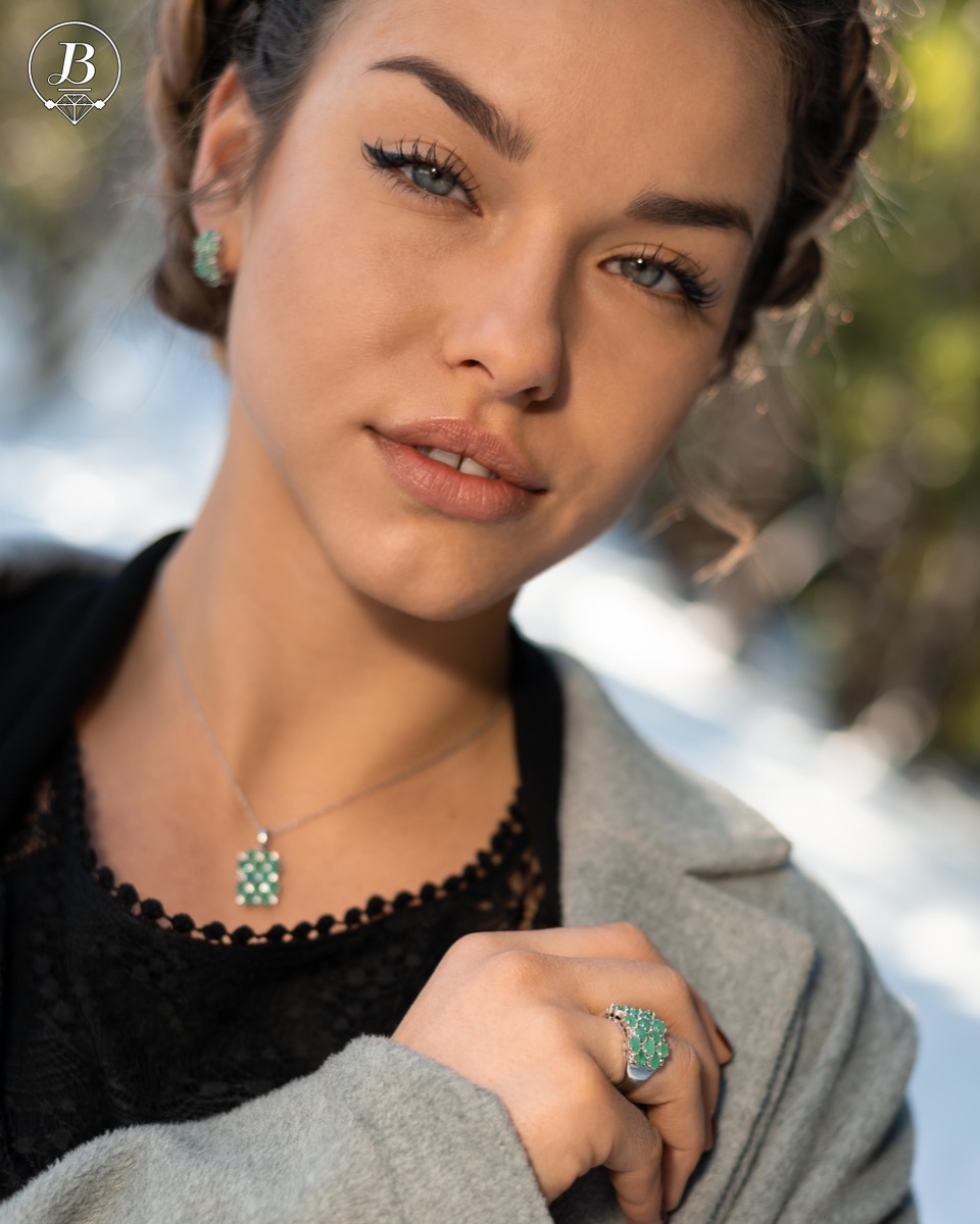 Women's ring with modern craftsmanship, combining numerous fine natural emerald stones, complemented by the sparkle of zircons and made entirely of rhodium-plated silver. In a charming set with matching necklace and earrings.