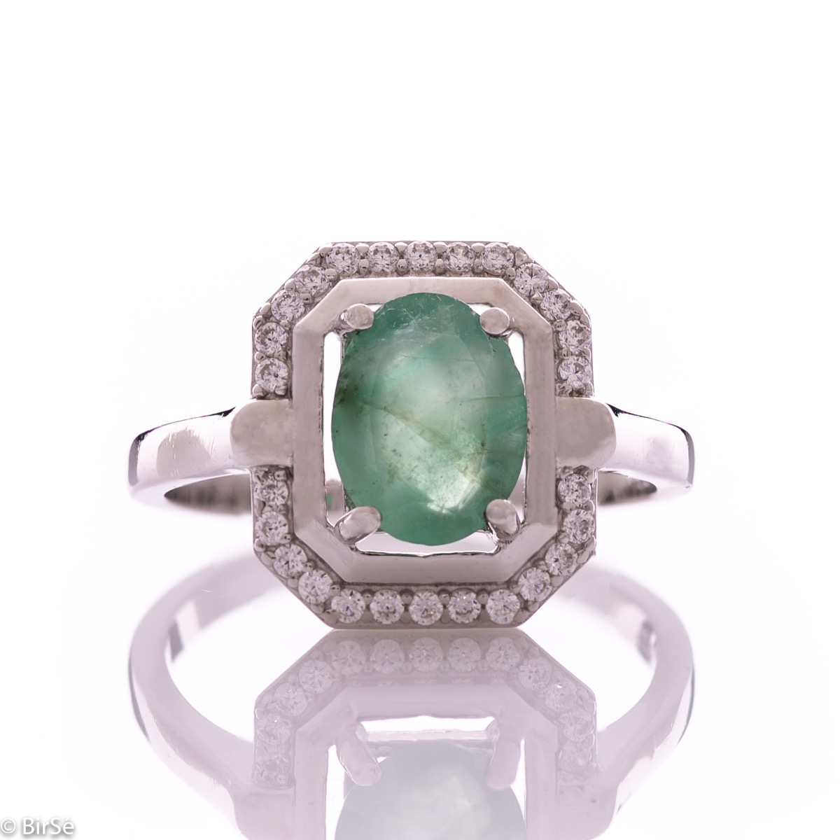 An elegant lady's ring made of rhodium-plated silver, combined with the gentle glow of a natural emerald stone, surrounded by sparkling zircons. It can be combined with a pendant and earrings of the same model.