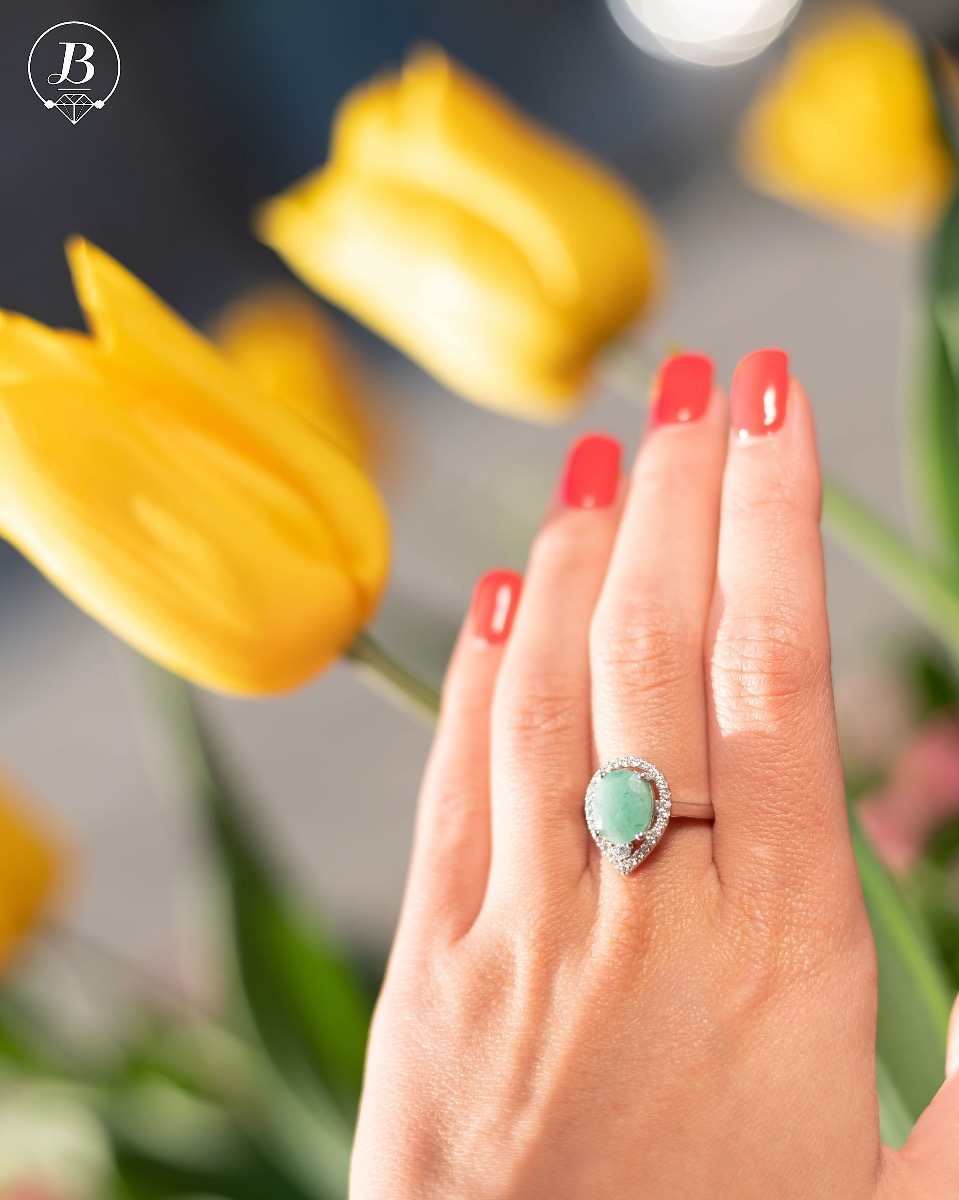 An elegant women's ring with spectacular craftsmanship combining refined rhodium-plated silver with a radiant natural emerald and sparkling zircons. Can be combined with earrings and pendant of the same model.