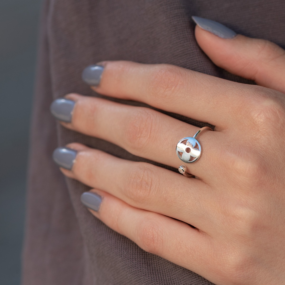 Beautifully crafted ring in sterling silver, adjustable pattern, ending at one end with a round element in the middle with a flower. At the other end, in a delicate fitting, a tiny zircon sparkles beautifully.