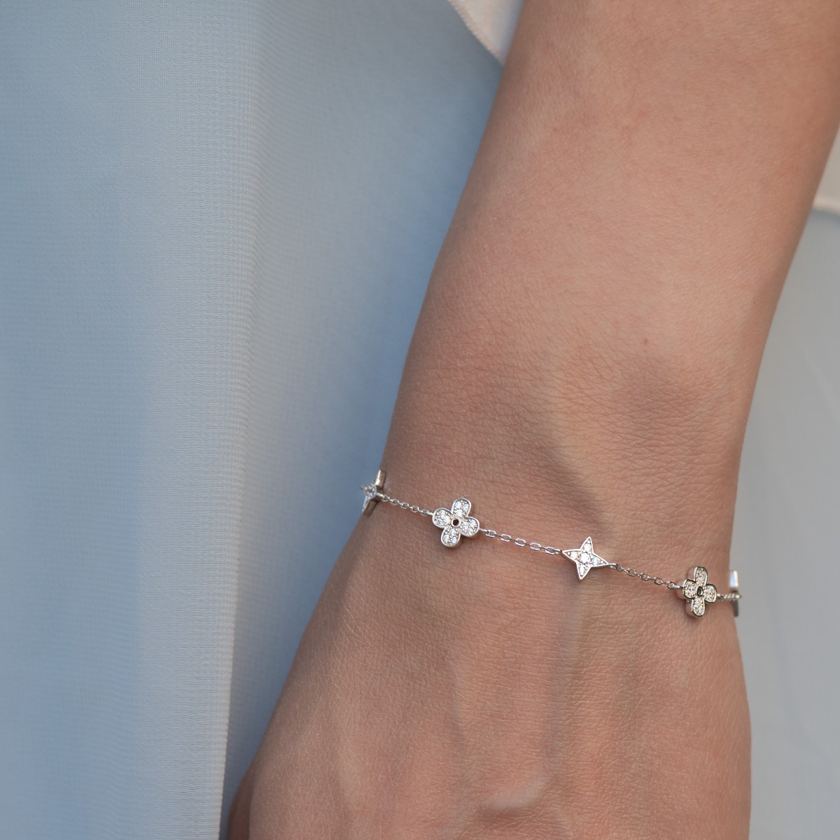 Stylish women's bracelet with adjustable size and delicate craftsmanship, combining refined rhodium-plated silver with delicate flower elements, complemented by sparkling zircons.