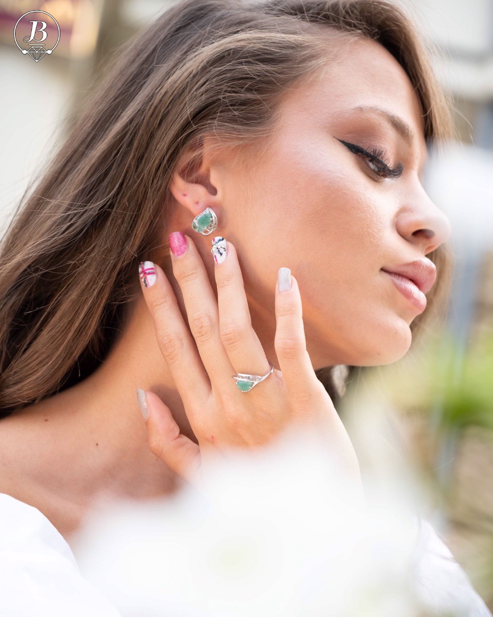 Captivating women's earrings with English clasp and beautiful curves and details crafted from soft rhodium-plated sterling silver, complemented by a radiant natural emerald stone in an exquisite teardrop shape. In a charming pendant and ring set.