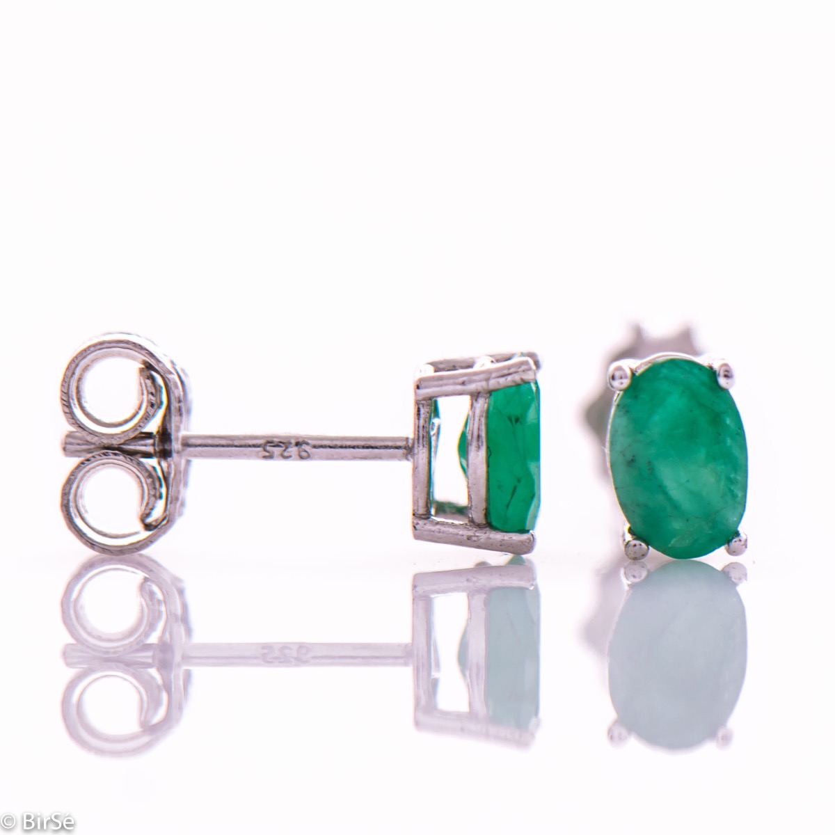 Elegant women's stud earrings with a clean design and a gentle combination of shiny rhodium silver with a radiant natural emerald stone in an elegant oval shape.