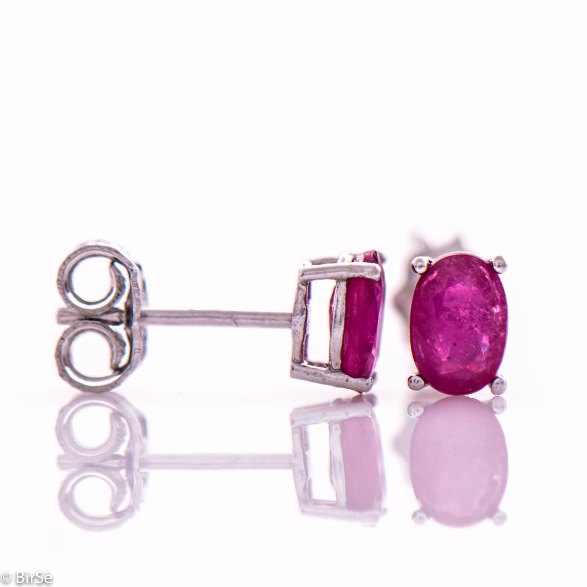 Elegant women's stud earrings with a clean design and a gentle combination of shiny rhodium silver with a radiant natural ruby ​​stone in an elegant oval shape.