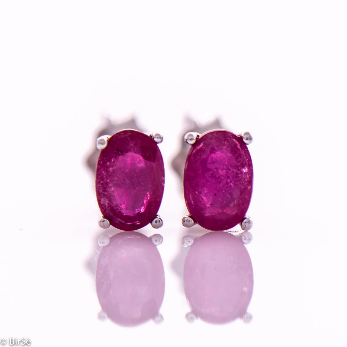 Elegant women's stud earrings with a clean design and a gentle combination of shiny rhodium silver with a radiant natural ruby ​​stone in an elegant oval shape.