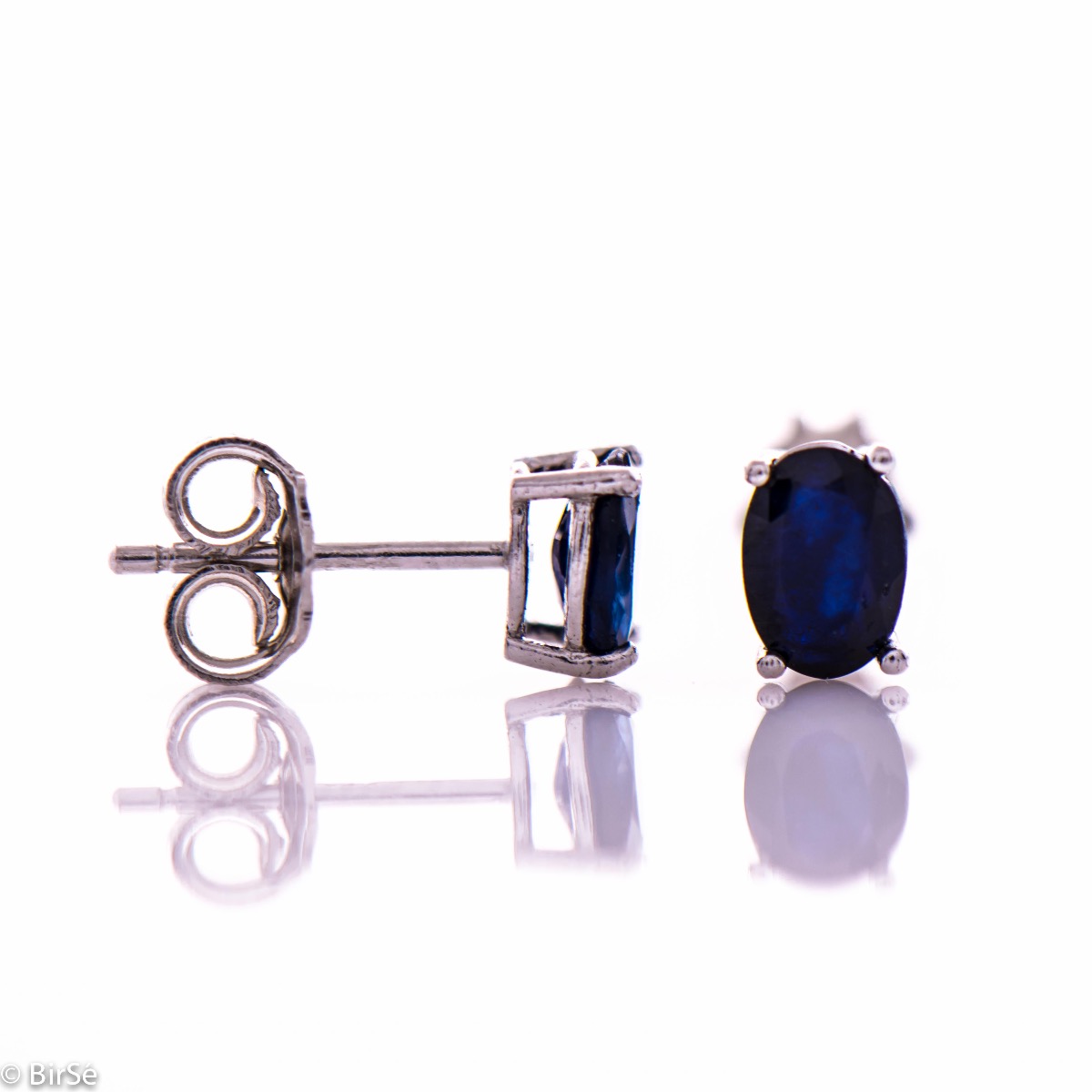 Elegant women's stud earrings with a clean design and a gentle combination of shiny rhodium silver with a radiant natural sapphire stone in an elegant oval shape.