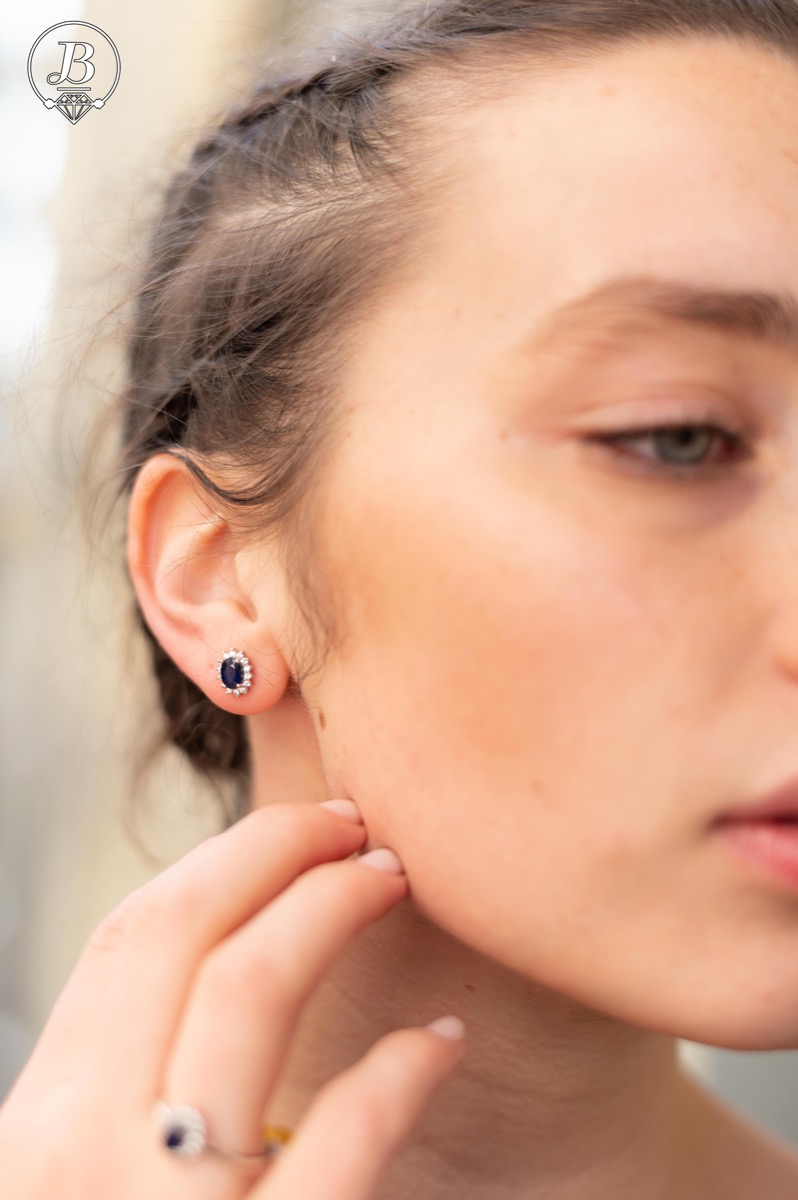 Delicate and radiant women's stud earrings with exquisite workmanship combining a unique natural sapphire, surrounded by sparkling zircons, with rhodium-plated silver. They can be combined with a ring, necklace and bracelet of the same model.