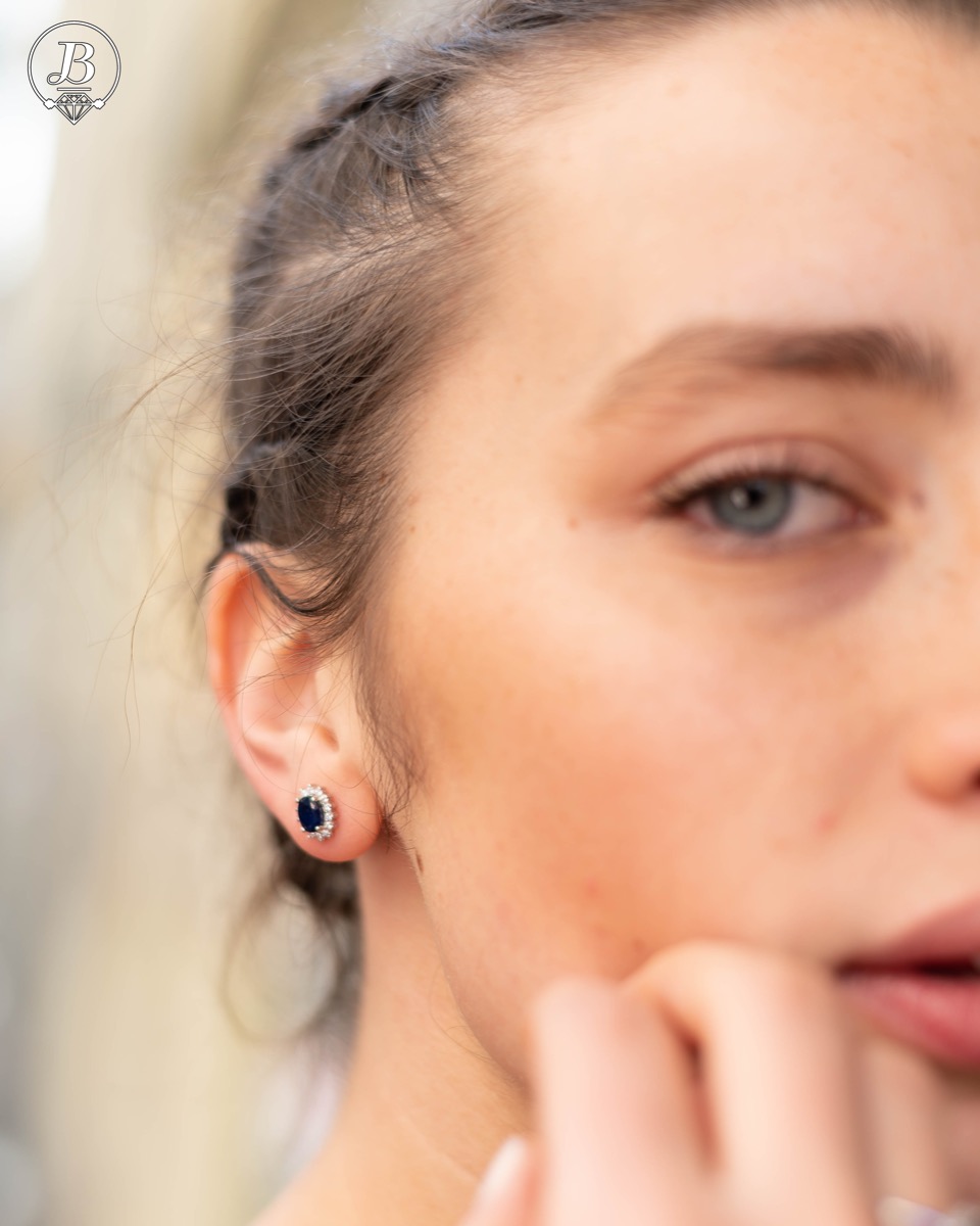 Delicate and radiant women's stud earrings with exquisite workmanship combining a unique natural sapphire, surrounded by sparkling zircons, with rhodium-plated silver. They can be combined with a ring, necklace and bracelet of the same model.