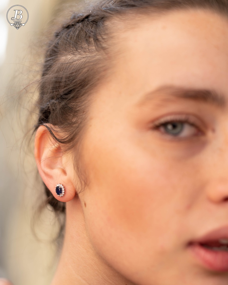 Delicate and radiant women's stud earrings with exquisite workmanship combining a unique natural sapphire, surrounded by sparkling zircons, with rhodium-plated silver. They can be combined with a ring, necklace and bracelet of the same model.