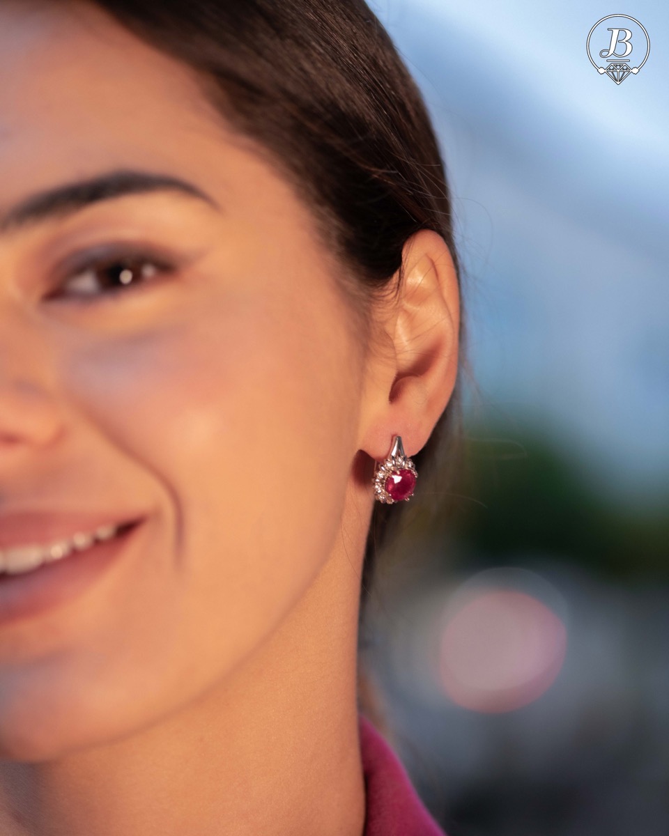 Extremely elegant ladies' earrings with English fastening and precise craftsmanship combining rhodium-plated silver with radiant natural ruby ​​and sparkling zircons. They can be combined with a pendant and a ring of the same model.