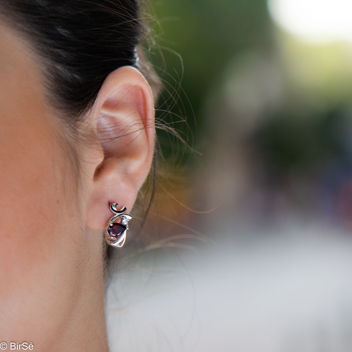 Elegant women's earrings with English clasp and spectacular curves made of beautiful rhodium silver, complemented by the sparkle of natural teardrop garnet and fine zircon. In an exclusive pendant and ring set.