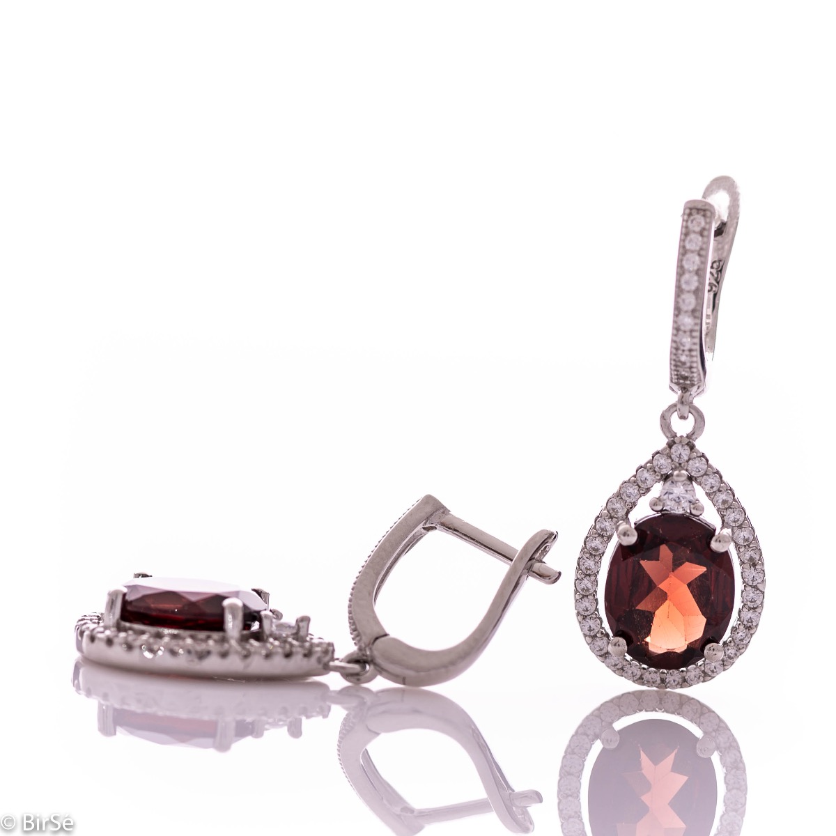 Elegant ladies' earrings with an English clasp and an impressive design combining delicate rhodium silver with a radiant natural garnet surrounded by sparkling zircons. They can be combined with a pendant and a ring of the same model.