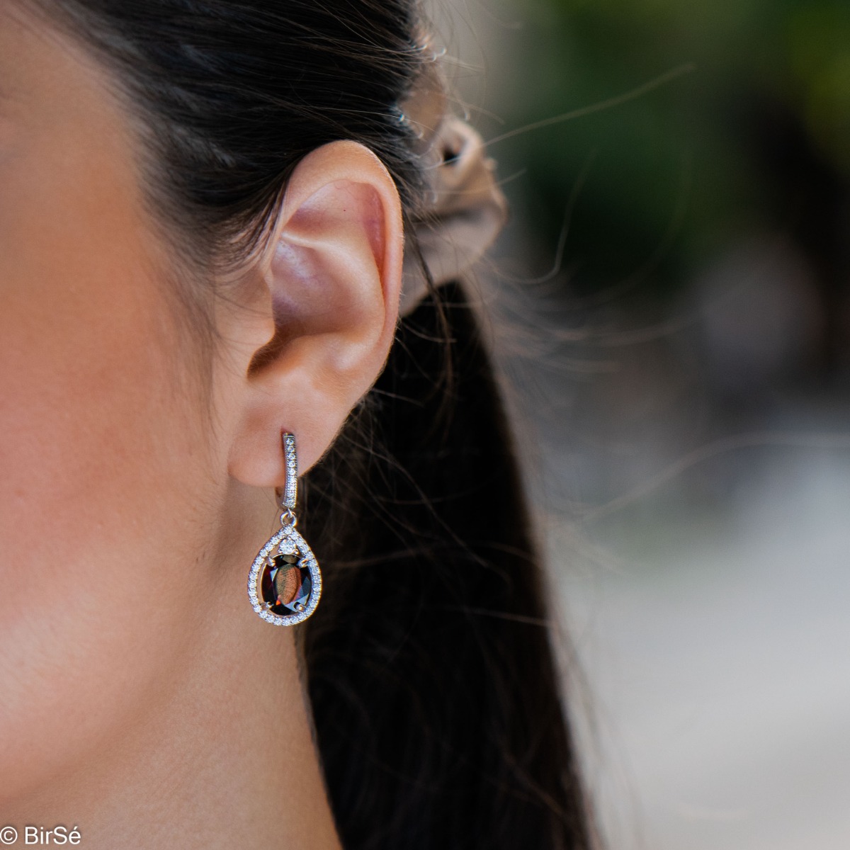 Elegant ladies' earrings with an English clasp and an impressive design combining delicate rhodium silver with a radiant natural garnet surrounded by sparkling zircons. They can be combined with a pendant and a ring of the same model.