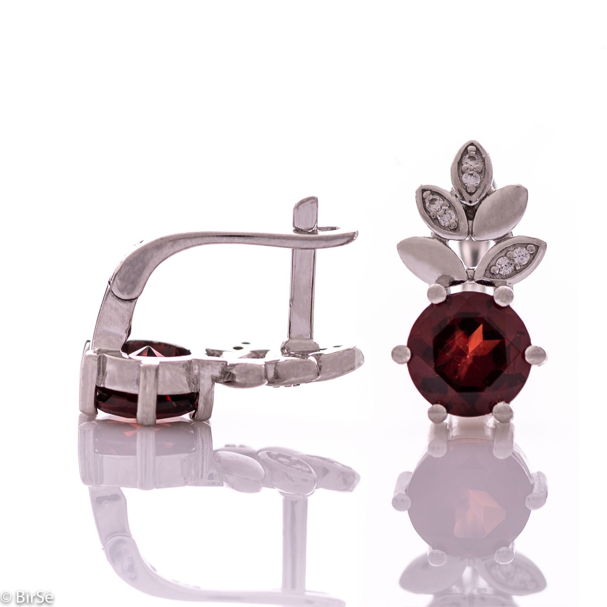 Delicate ladies' earrings with an English clasp and an exclusive design combining a radiant natural garnet surrounded by petals of zircons and made entirely of rhodium-plated silver. They can be combined with a pendant and a ring of the same model.