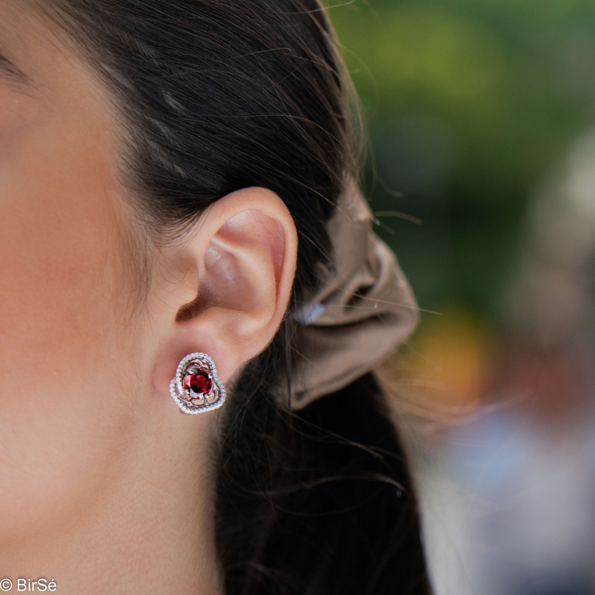 Elegant women's earrings with English fastening and exquisite workmanship entirely of rhodium-plated silver complemented by the glow of natural garnet and sparkling zircons. They can be combined with a ring and pendant of the same model.