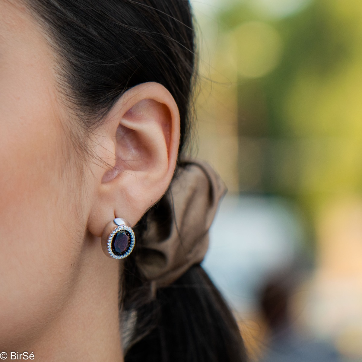 Elegant women's earrings with an English clasp and a classic design combining a radiant natural garnet surrounded by sparkling zircons with soft rhodium silver. They can be combined with a ring and pendant of the same model.