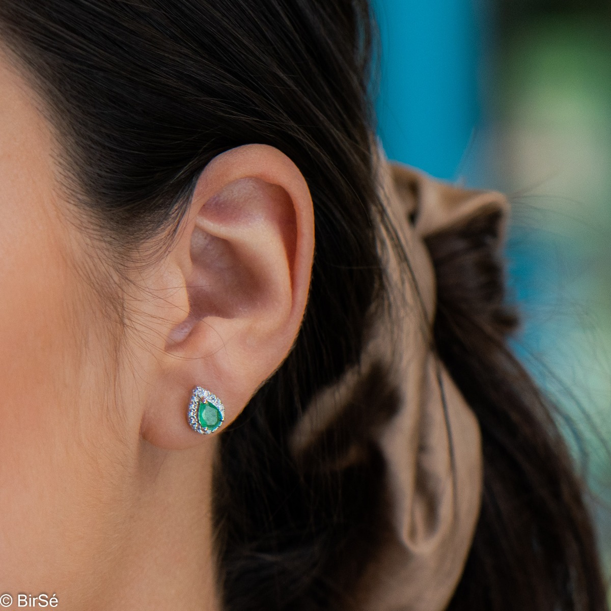 Radiant stud earrings delicately crafted in teardrop shape and fine rhodium silver, complemented by exquisite natural emerald and sparkling zircons.