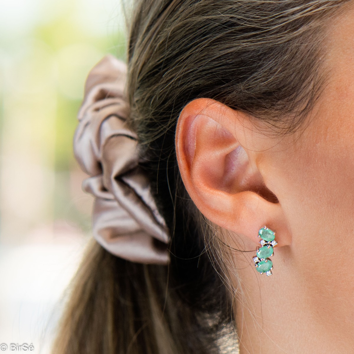 Delicately radiant English clasp earrings for women, finely crafted entirely in beautiful rhodium-plated sterling silver, complemented by exquisite natural emerald and sparkling zircons. Part of an elegant pendant and ring set.