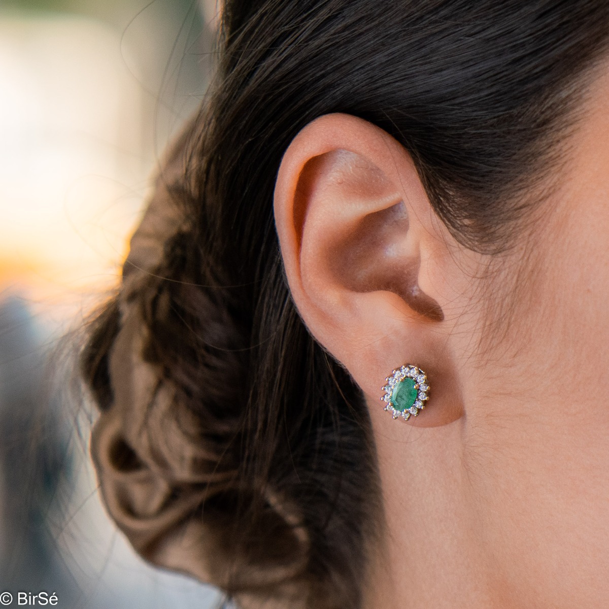 Delicate and radiant women's stud earrings with exquisite workmanship combining a unique natural emerald, surrounded by sparkling zircons, with rhodium-plated silver. They can be combined with a ring, necklace and bracelet of the same model.