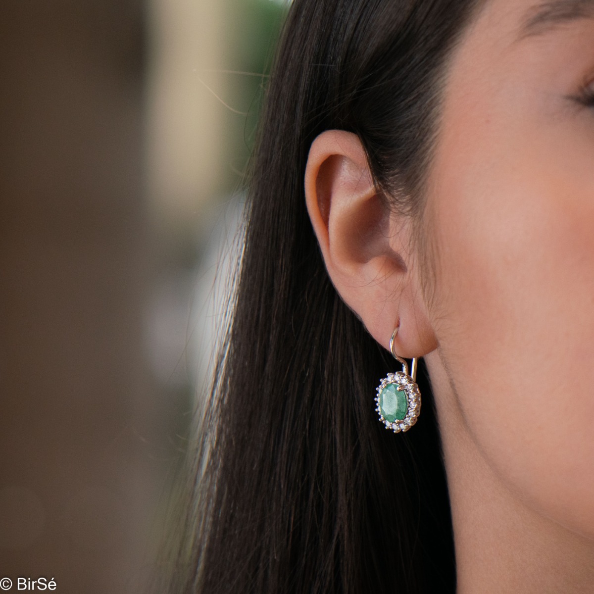 Exclusive women's earrings with exquisite workmanship combining delicate rhodium silver with a radiant natural emerald surrounded by sparkling zircons.