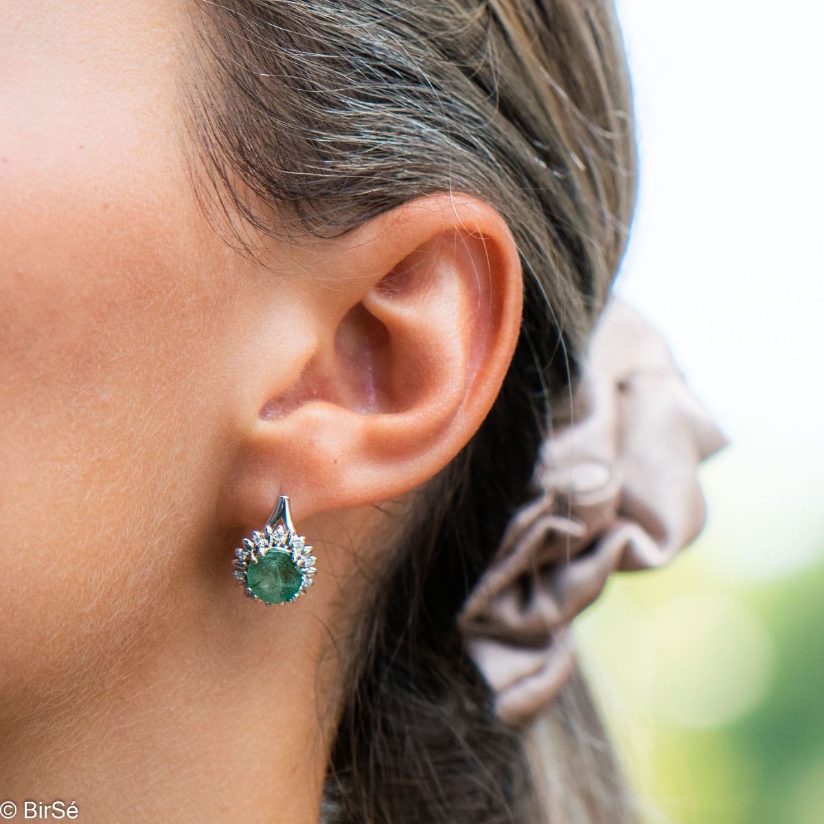 Extremely elegant ladies' earrings with English fastening and precise craftsmanship combining rhodium-plated silver with radiant natural emerald and sparkling zircons. They can be combined with a pendant and a ring of the same model.