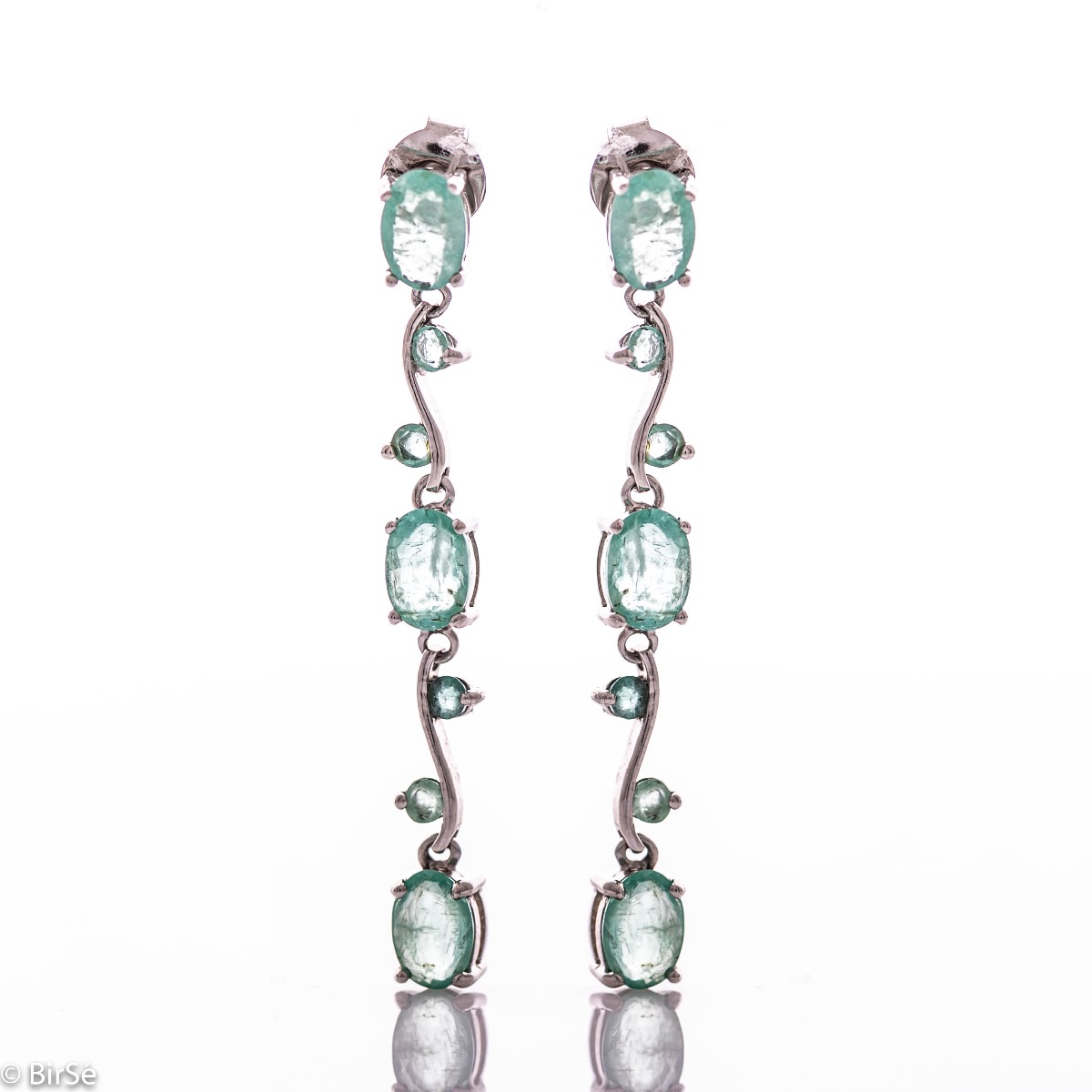 Extremely impressive dangling earrings with delicate workmanship combining numerous natural emerald stones with shiny rhodium silver.