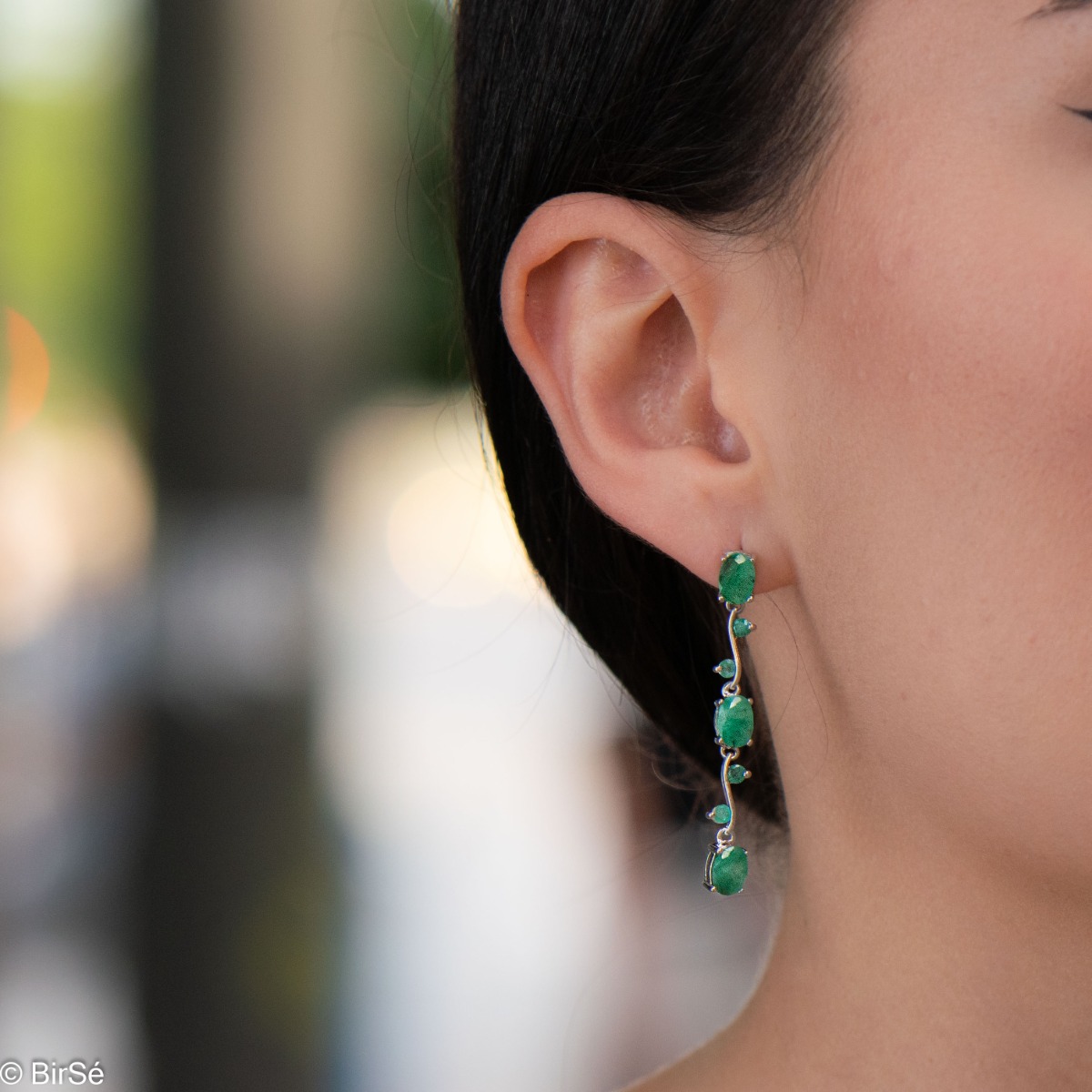 Extremely impressive dangling earrings with delicate workmanship combining numerous natural emerald stones with shiny rhodium silver.