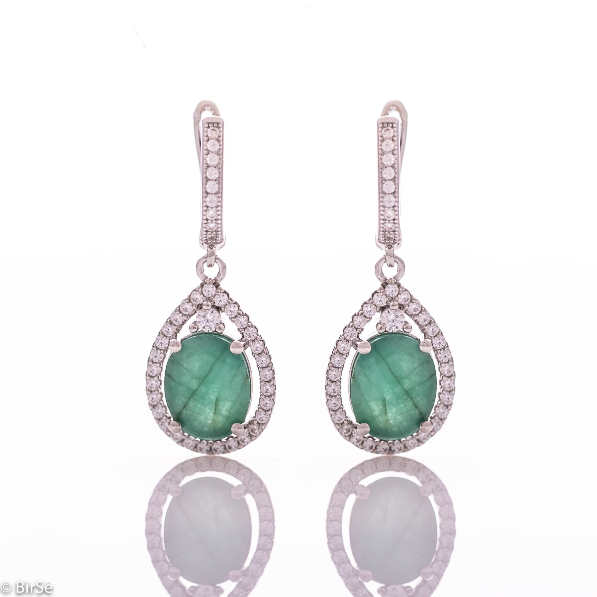 Elegant ladies' earrings with an English clasp and an impressive design combining delicate rhodium silver with a radiant natural emerald surrounded by sparkling zircons. They can be combined with a pendant and a ring of the same model.