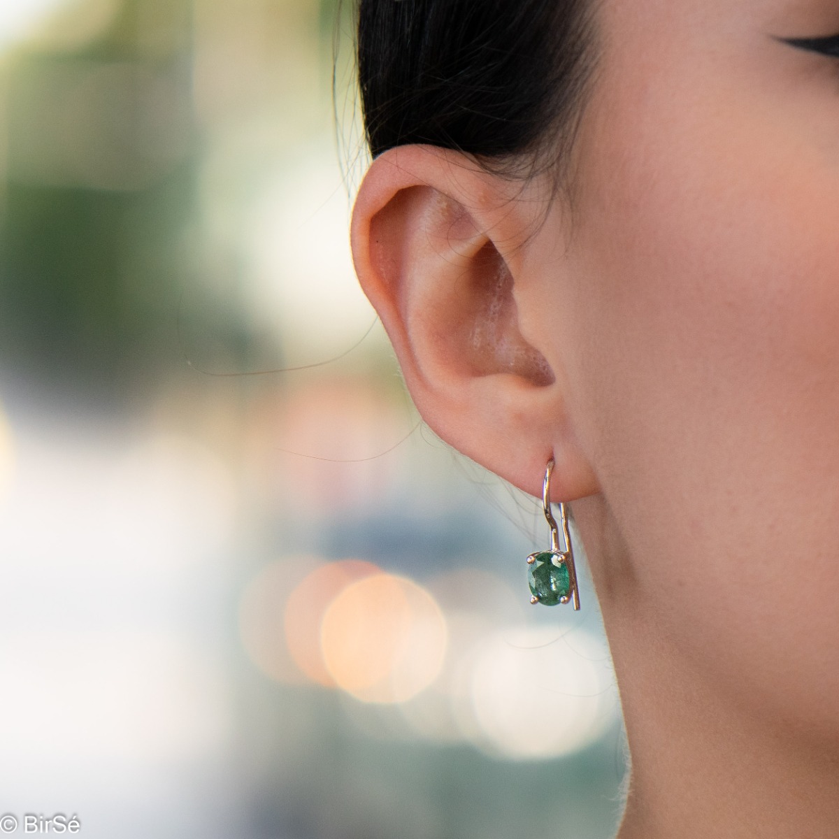 Delicate women's earrings with a clean and precise design combining shiny rhodium silver with a radiant natural emerald.