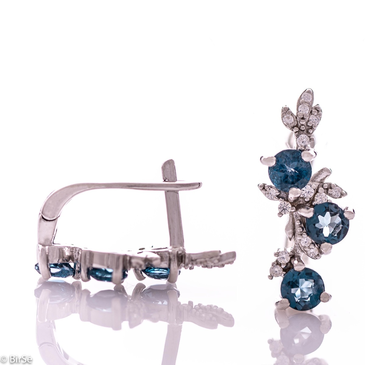 Exclusive women's earrings with English clasp and delicate design, combining craftsmanship entirely from rhodium silver, complemented by natural stones London topaz and zircons. They can be combined with a pendant and a ring of the same model.