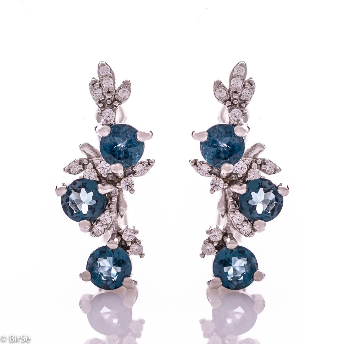 Exclusive women's earrings with English clasp and delicate design, combining craftsmanship entirely from rhodium silver, complemented by natural stones London topaz and zircons. They can be combined with a pendant and a ring of the same model.