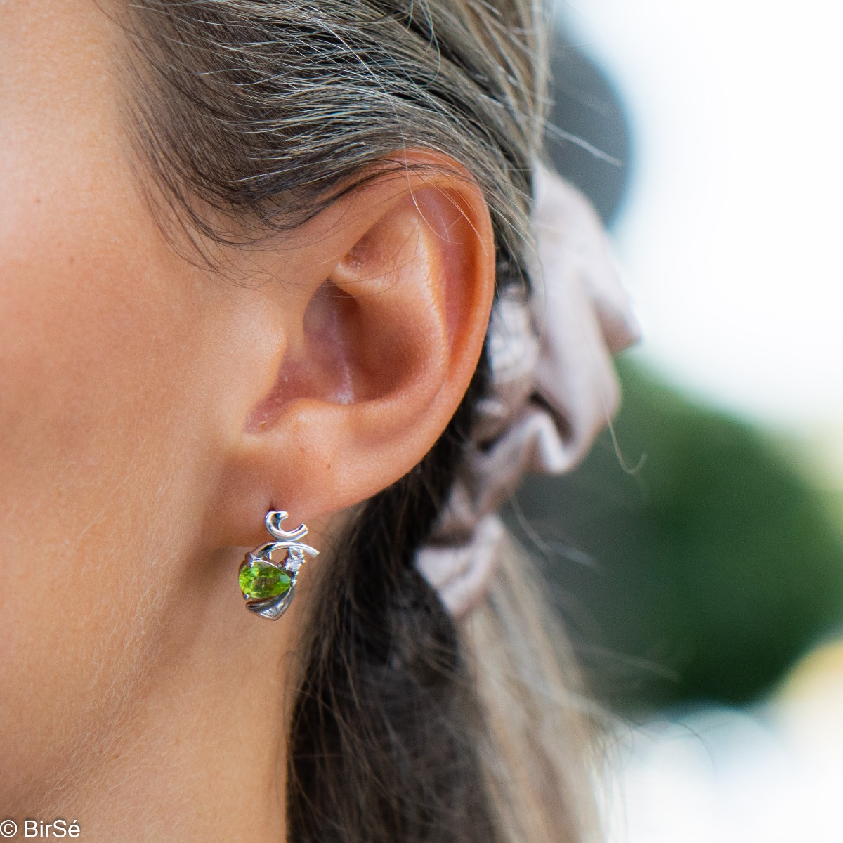 Exquisite women's earrings with English clasp and spectacular craftsmanship, interweaving a radiant natural peridot stone, in a beautiful teardrop shape, with sparkling zircon and delicate curves of rhodium silver. In a charming ring and pendant set.