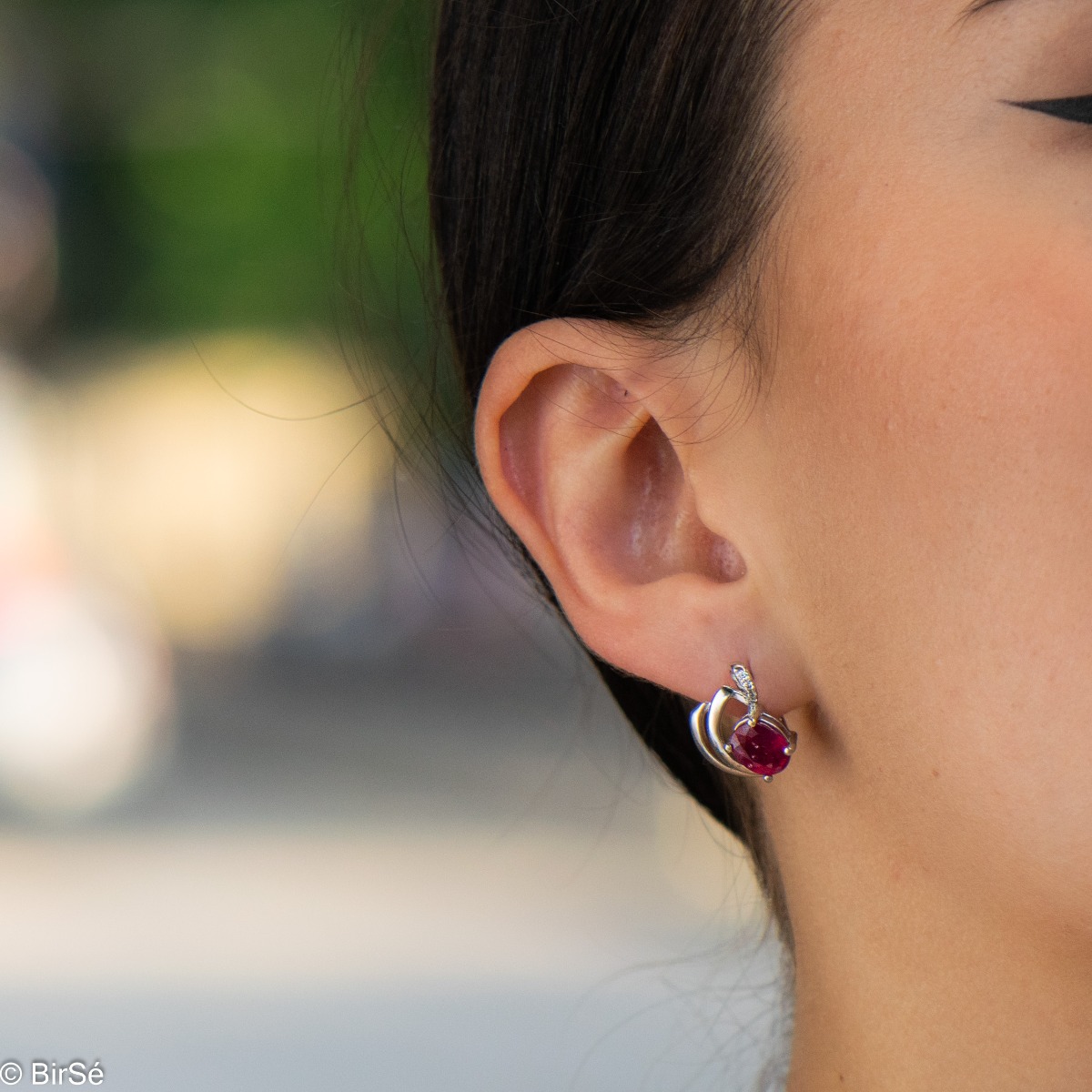 Sophisticated women's earrings with a non-standard and modern design, made entirely of beautiful rhodium-plated silver, complemented by a radiant natural ruby ​​stone and delicate zircons. In an exclusive sterling silver pendant and ring set.