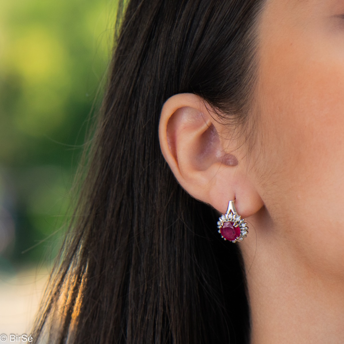 Extremely elegant ladies' earrings with English fastening and precise craftsmanship combining rhodium-plated silver with radiant natural ruby ​​and sparkling zircons. They can be combined with a pendant and a ring of the same model.