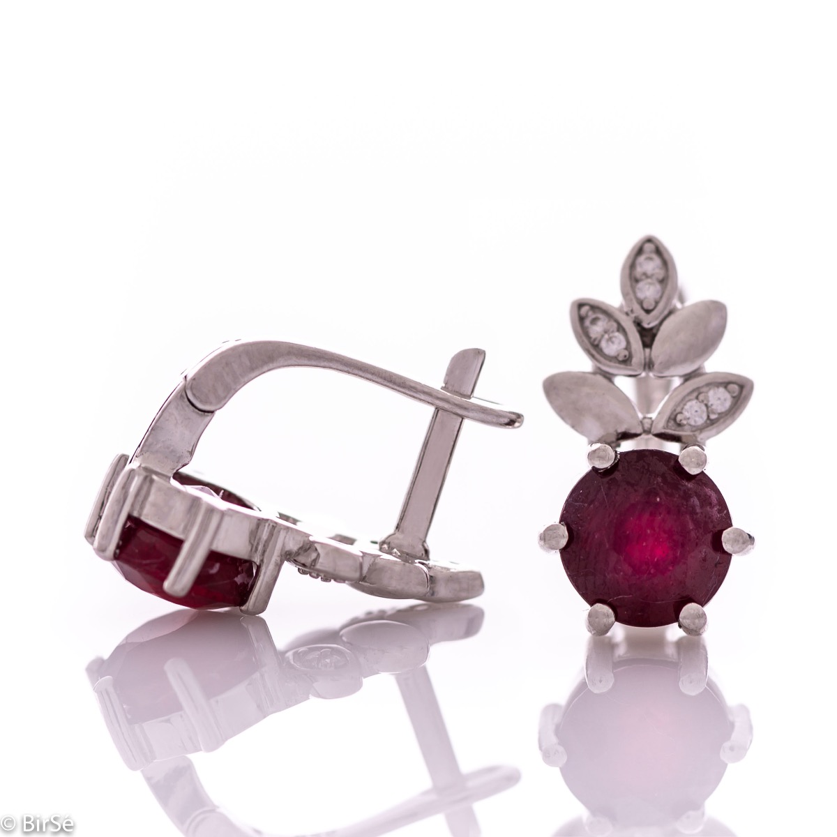 Delicate ladies' earrings with an English clasp and an exclusive design combining a radiant natural ruby ​​surrounded by cubic zirconia petals and made entirely of rhodium-plated silver. They can be combined with a pendant and a ring of the same model.