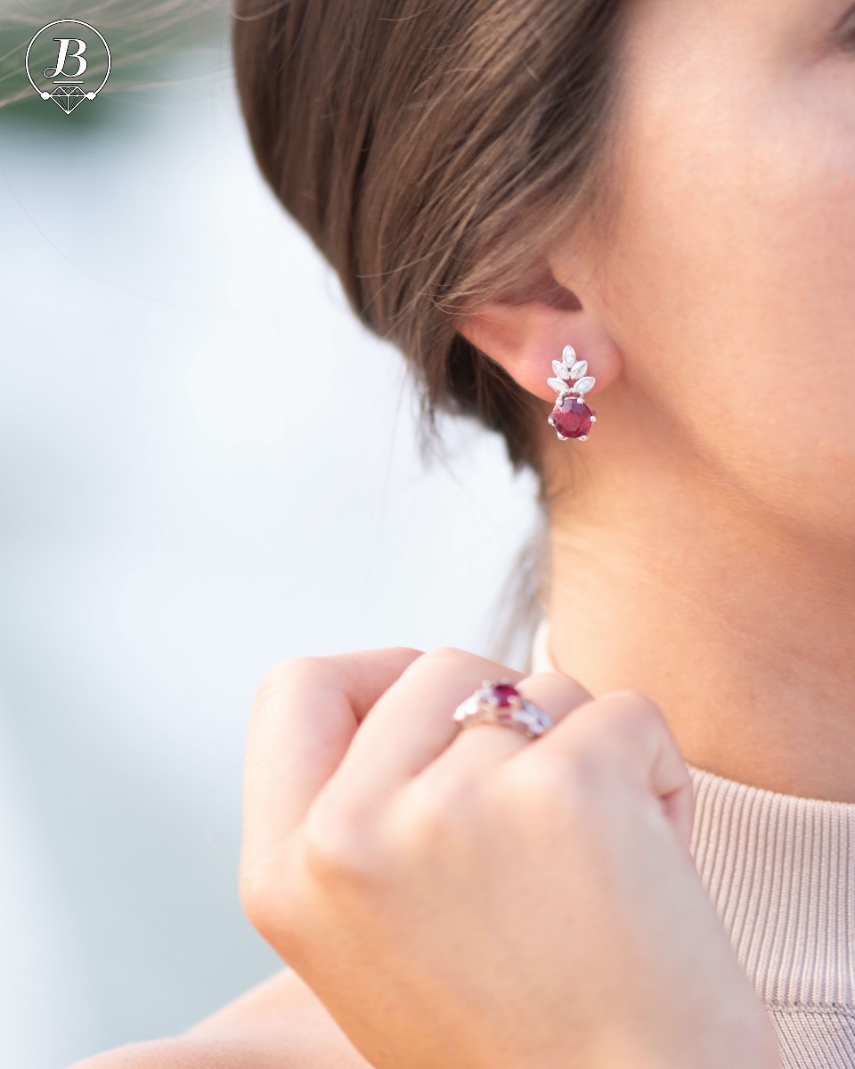 Delicate ladies' earrings with an English clasp and an exclusive design combining a radiant natural ruby ​​surrounded by cubic zirconia petals and made entirely of rhodium-plated silver. They can be combined with a pendant and a ring of the same model.