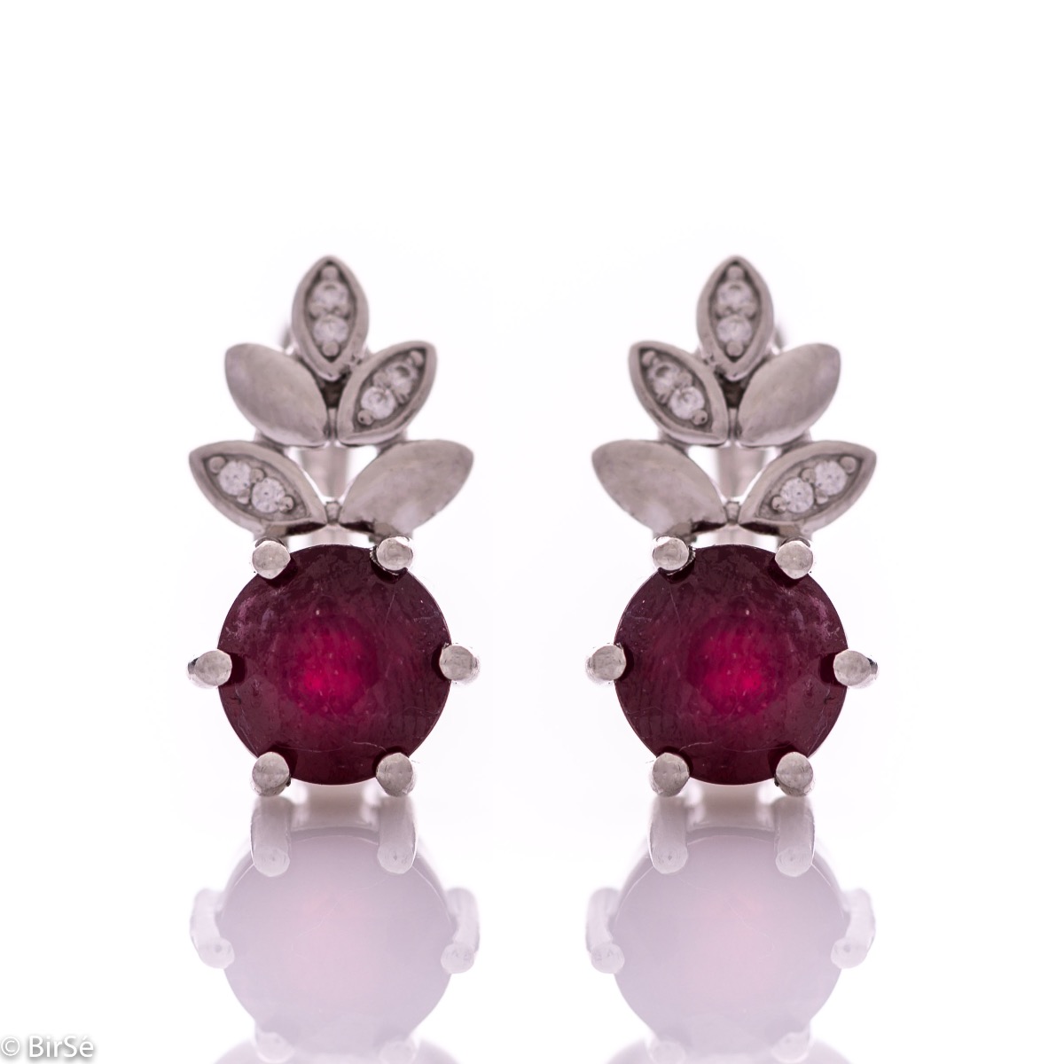 Delicate ladies' earrings with an English clasp and an exclusive design combining a radiant natural ruby ​​surrounded by cubic zirconia petals and made entirely of rhodium-plated silver. They can be combined with a pendant and a ring of the same model.