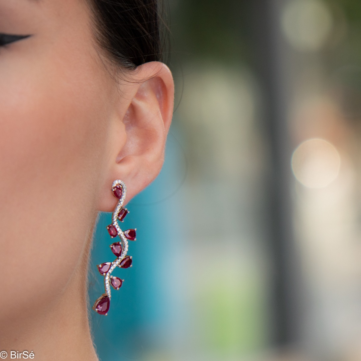 Dangling women's earrings on a pin with exquisite workmanship combining delicate rhodium silver with numerous natural ruby ​​stones and sparkling zircons.