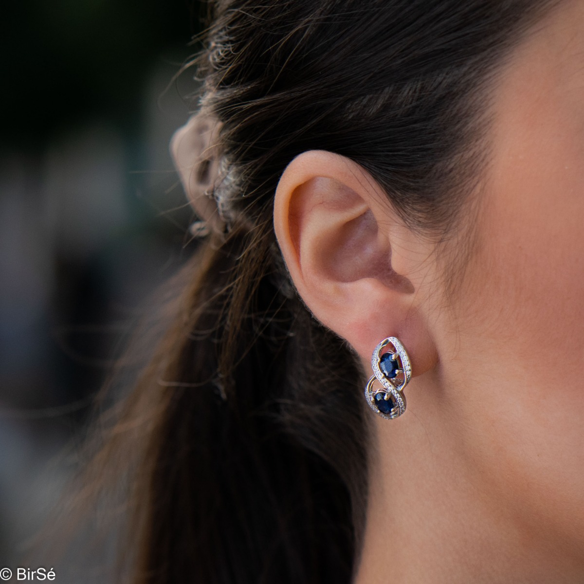 Stunning earrings beautifully crafted in rhodium-plated sterling silver with an infinity shape, exquisitely embellished with sparkling cubic zirconias surrounding magnetic sapphires. Complete with a ring of the same design.