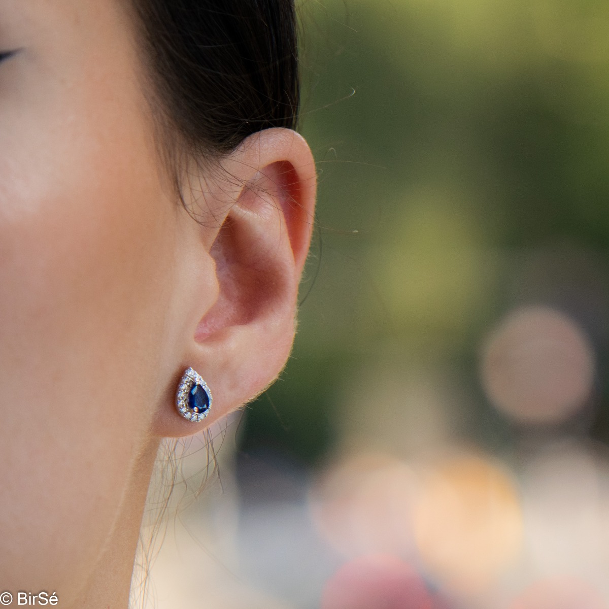 Radiant stud earrings delicately crafted in a teardrop shape and finely rhodium-plated sterling silver, complemented by exquisite natural sapphires and sparkling zircons.