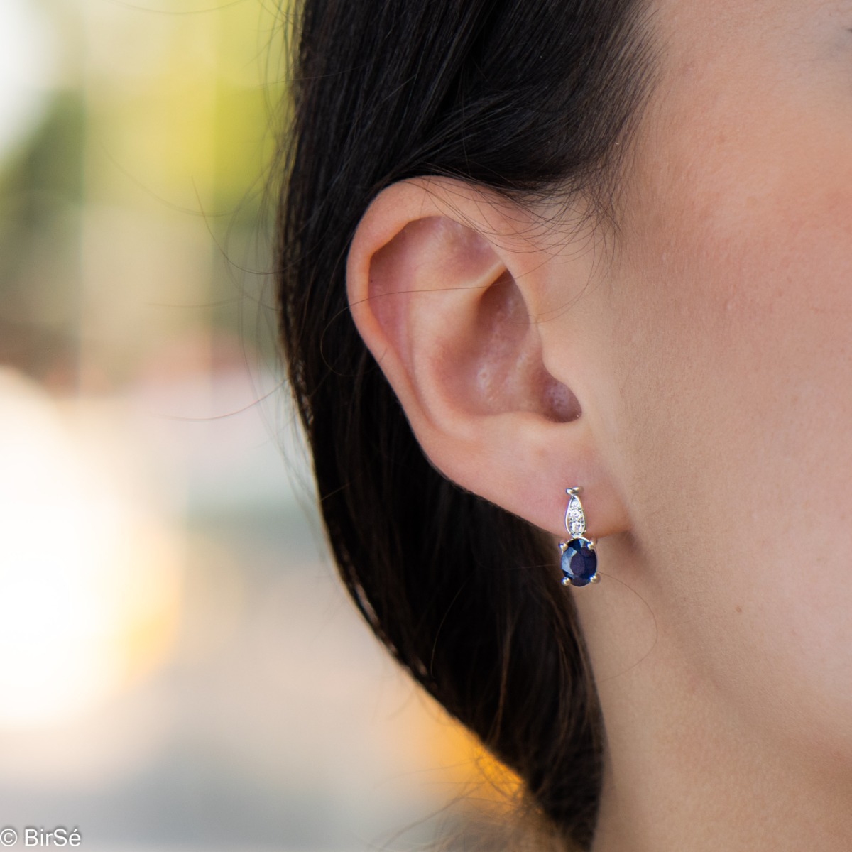 Fine ladies earrings with English clasp and delicate intertwining of radiant natural sapphire with sparkling zircons and exquisite craftsmanship of beautiful rhodium silver. In an exclusive ring and pendant set.