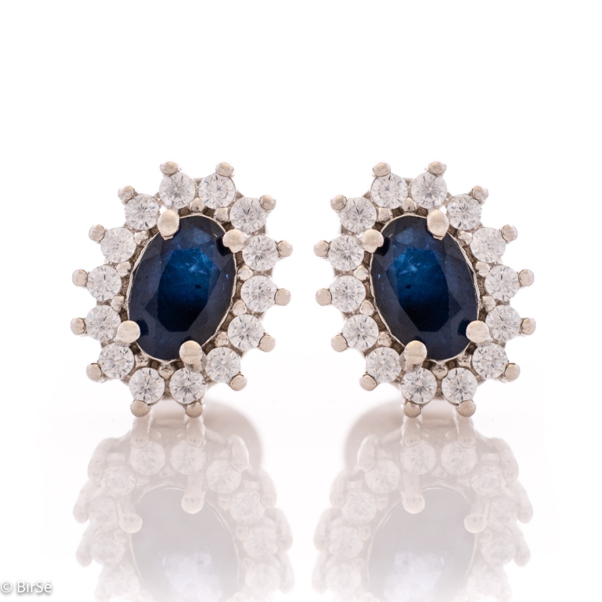 Delicate and radiant women's stud earrings with exquisite workmanship combining a unique natural sapphire, surrounded by sparkling zircons, with rhodium-plated silver. They can be combined with a ring, necklace and bracelet of the same model.