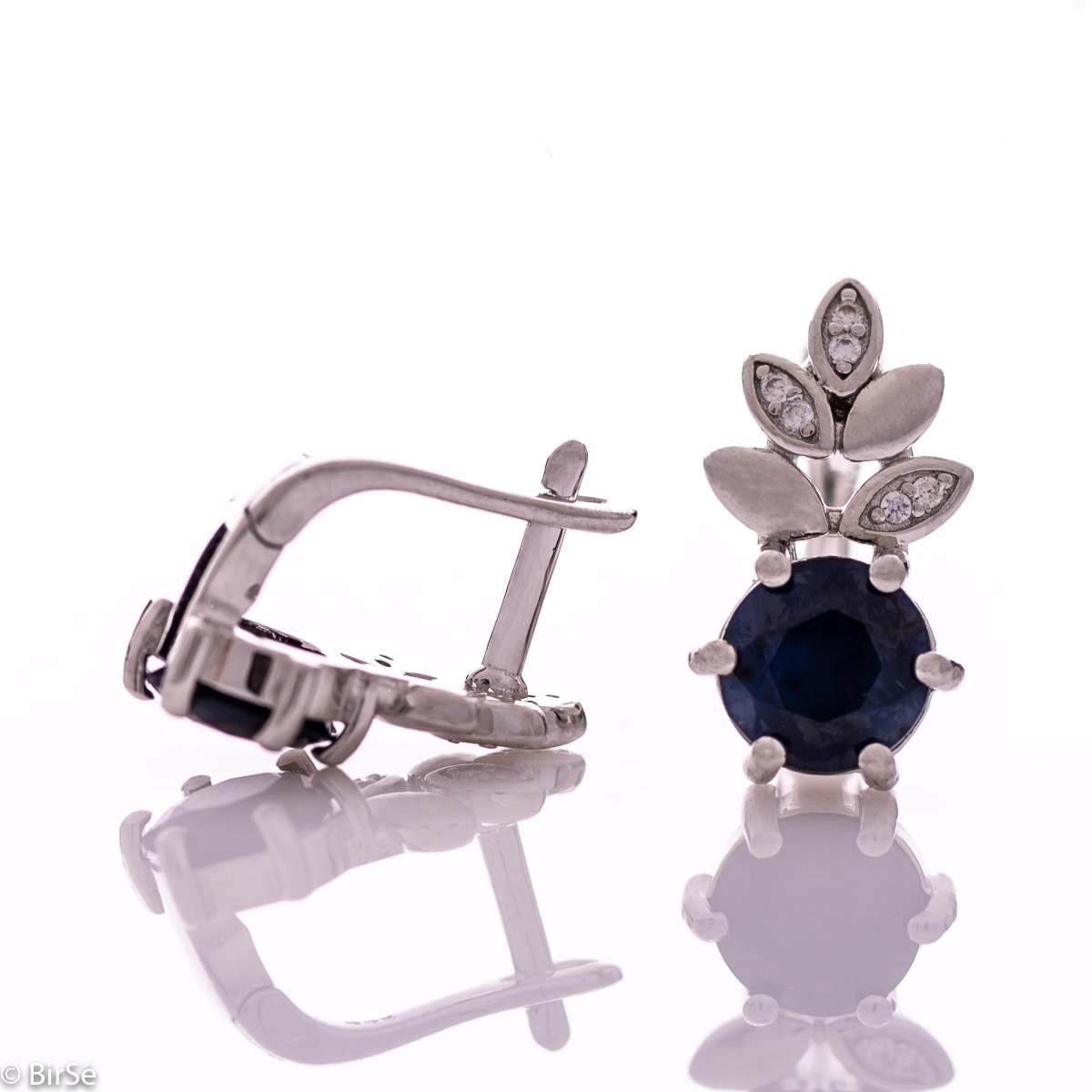 Delicate women's earrings with an English clasp and an exclusive design combining a radiant natural sapphire surrounded by cubic zirconia petals and made entirely of rhodium-plated silver. They can be combined with a pendant and a ring of the same model.