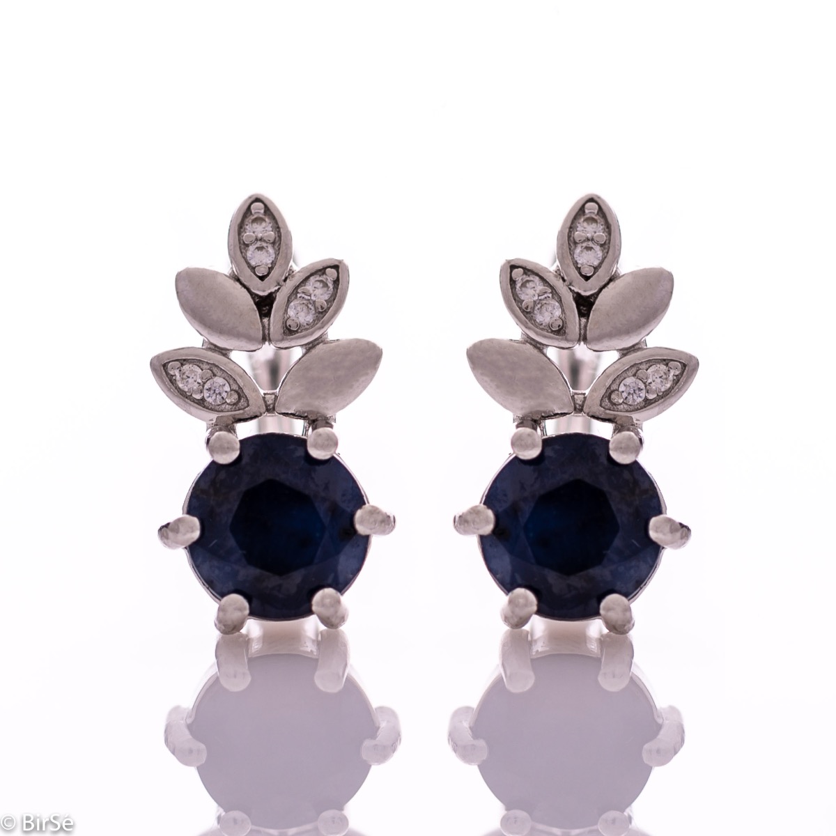 Delicate women's earrings with an English clasp and an exclusive design combining a radiant natural sapphire surrounded by cubic zirconia petals and made entirely of rhodium-plated silver. They can be combined with a pendant and a ring of the same model.