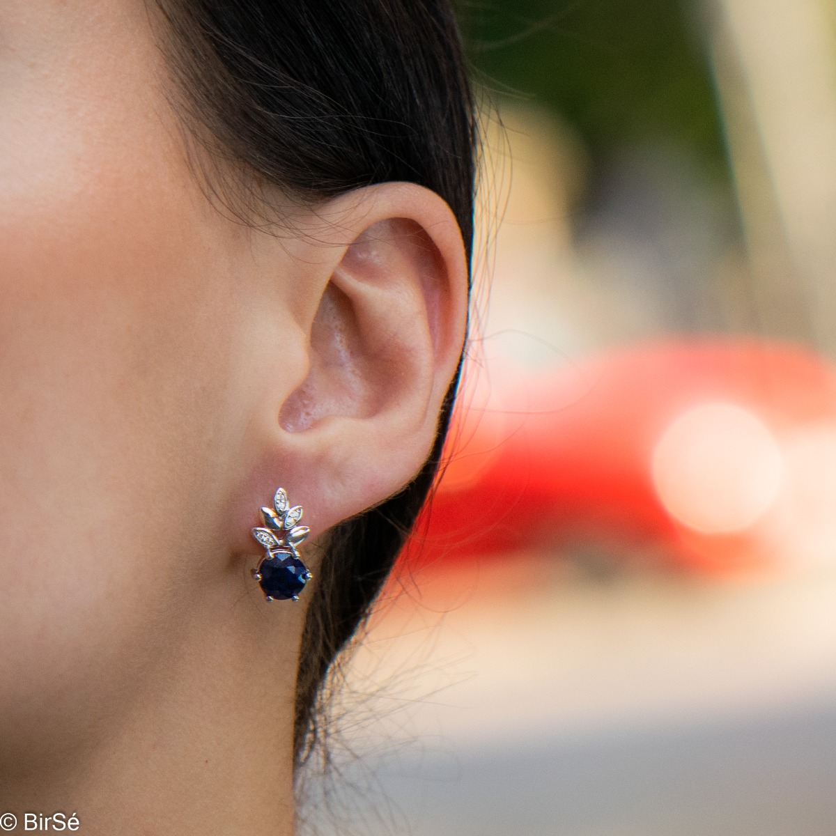 Delicate women's earrings with an English clasp and an exclusive design combining a radiant natural sapphire surrounded by cubic zirconia petals and made entirely of rhodium-plated silver. They can be combined with a pendant and a ring of the same model.