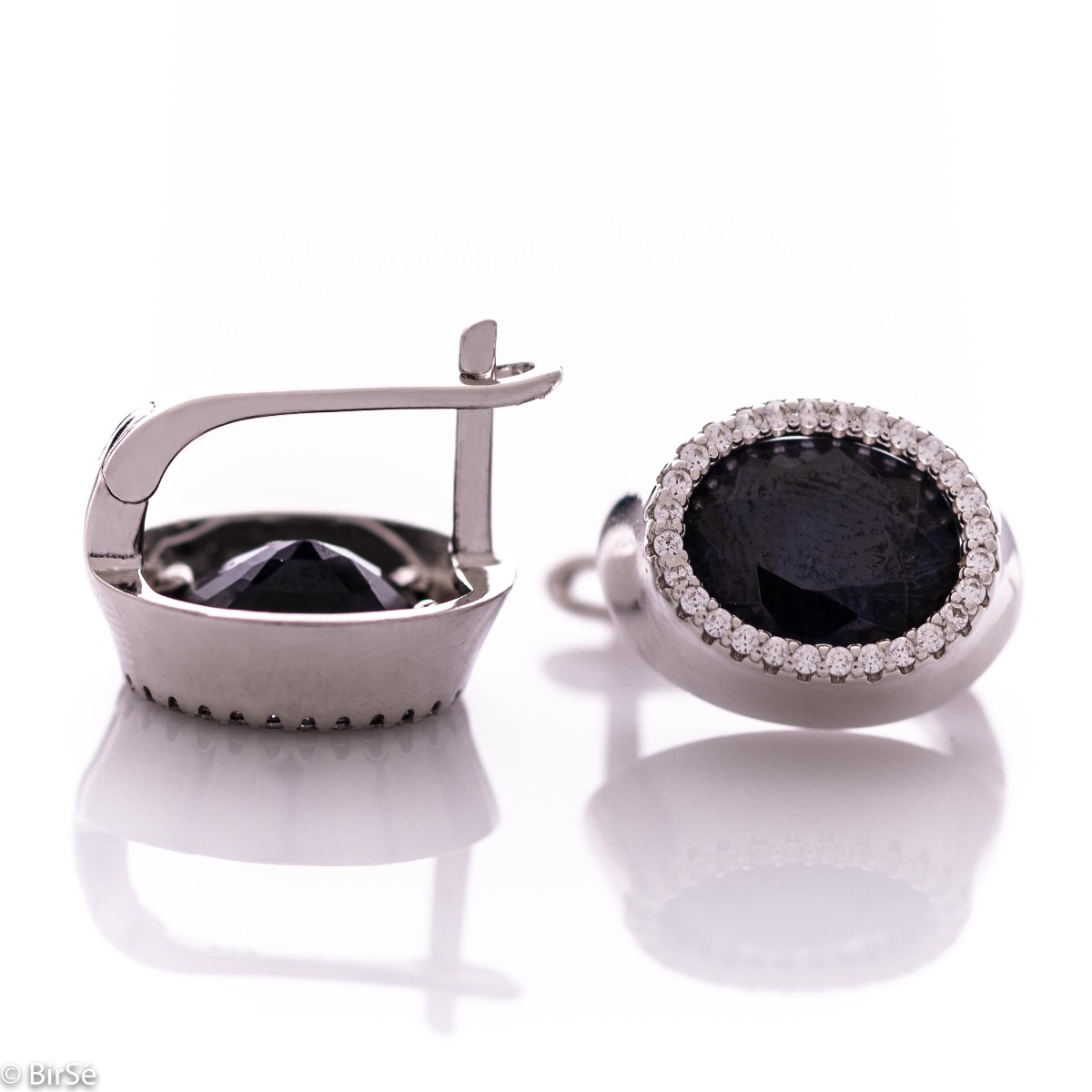 Elegant women's earrings with an English clasp and a classic design combining a radiant natural sapphire surrounded by sparkling zircons with delicate rhodium silver. They can be combined with a ring and pendant of the same model.