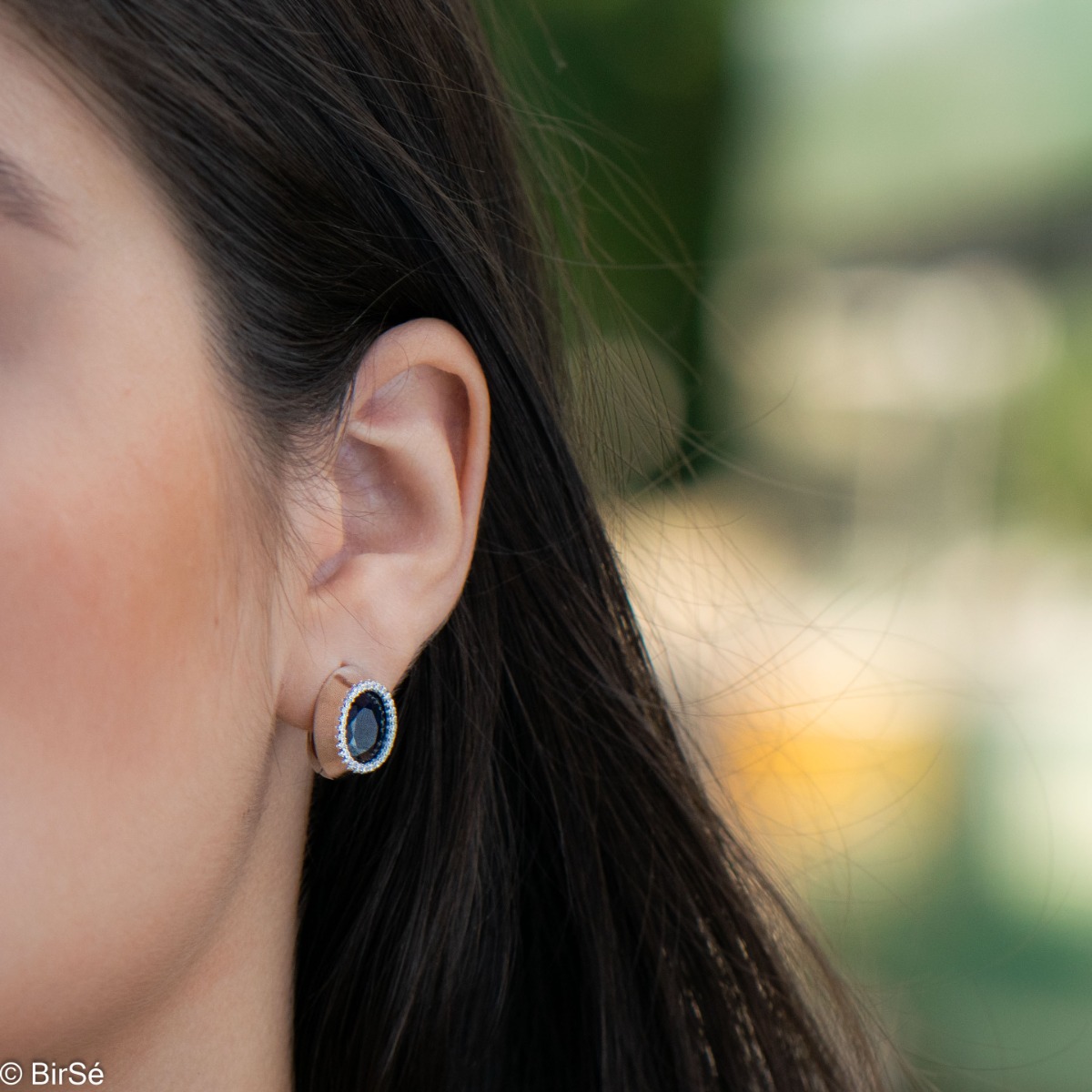 Elegant women's earrings with an English clasp and a classic design combining a radiant natural sapphire surrounded by sparkling zircons with delicate rhodium silver. They can be combined with a ring and pendant of the same model.