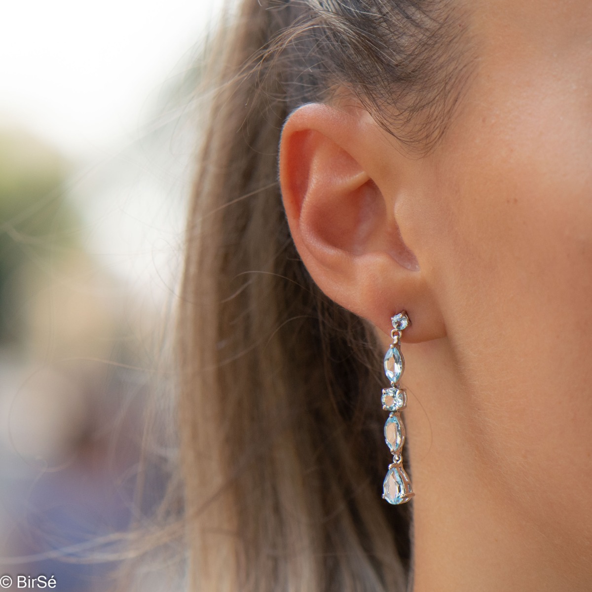 Exquisite earrings that will add sparkle to any look! Irresistible dangle earrings are made of soft rhodium silver and sparkling natural topaz, in a sky blue color.