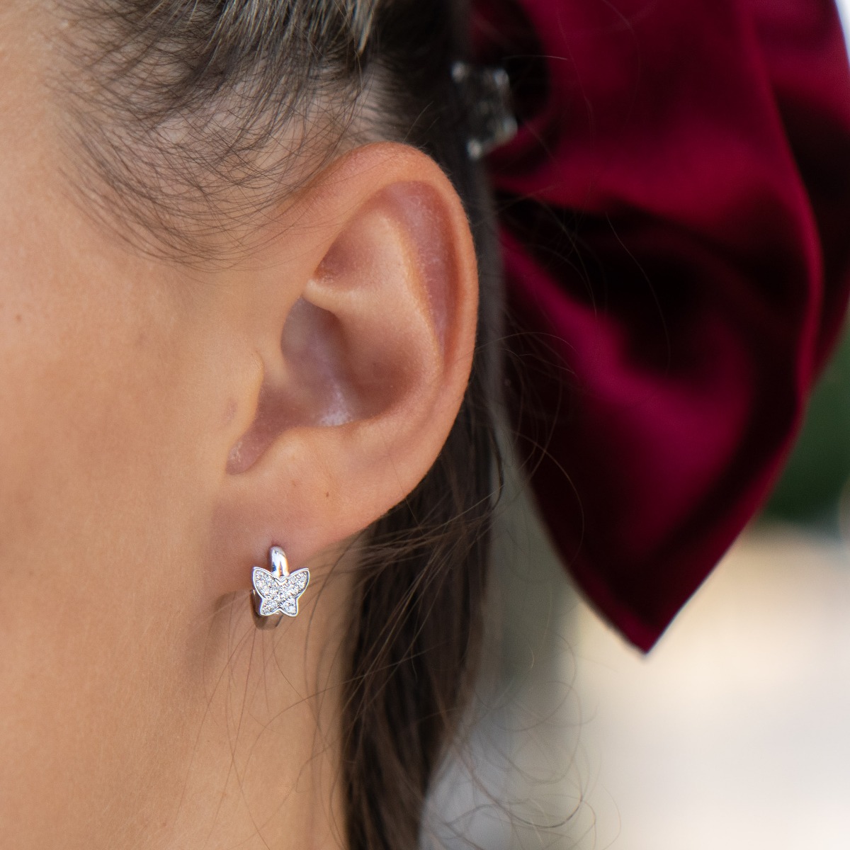 Fine women's earrings in sparkling rhodium silver and zircons, with a delicate butterfly on an elegant hoop. English fastening - preferred for children and comfortable for ladies.